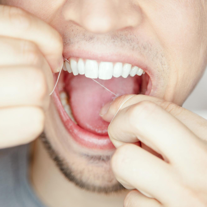 male-hand-cleaning-dislodging-food-stuck-teeth.jpg